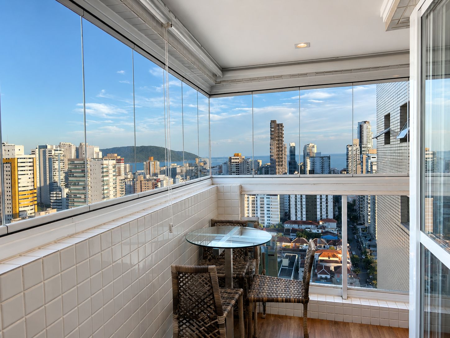 Varanda envidraçada com mesa e cadeiras e vista da cidade